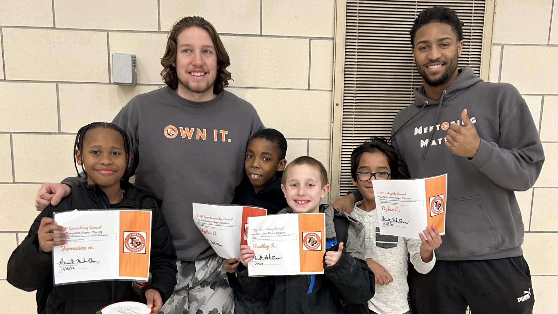 Two TCP mentors with four students holding certificates.